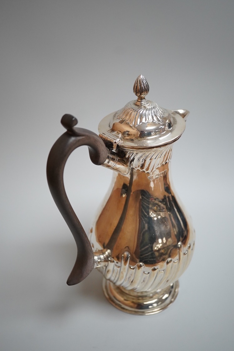 An Edwardian demi-fluted silver baluster hot water jug, William Hutton & Sons, London, 1902, height 21cm, 13.4oz.